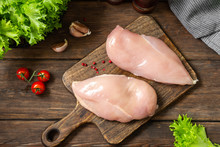 Chicken Breast Fillet On A Wooden Board On A Brown Wooden Table. Raw Chicken Breast. Top View 