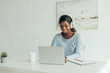 © LIGHTFIELD STUDIOS - smiling african american freelancer in wireless headphones working on laptop at home