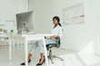 © LIGHTFIELD STUDIOS - young african american freelancer in white blouse, jeans and high heeled shoes looking at computer monitor at home