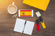 flag and coat of arms of spain, smartphone, wireless headphones, spanish textbook, notepad on a working wooden brown table, study concept 