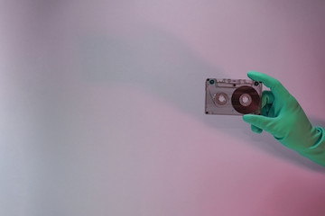 Poster - Green Hand holding audio cassette tape in the color light. Beautiful minimal in neon light. Minimalism retro style concept. Background pattern for design.