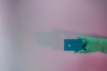 Poster - Green Hand holding audio cassette tape in the color light. Beautiful minimal in neon light. Minimalism retro style concept. Background pattern for design.