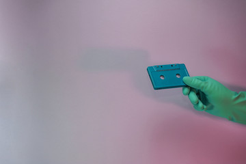 Poster - Green Hand holding audio cassette tape in the color light. Beautiful minimal in neon light. Minimalism retro style concept. Background pattern for design.