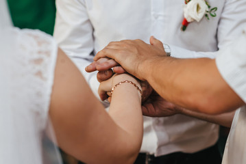 Wall Mural - hands of the bride and groom and the Holy father at the wedding ceremony