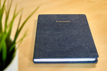 Planner or organizer notebook with jeans texture material cover, a diary to make appointment meeting or manage timetable close book on a wooden office desk 