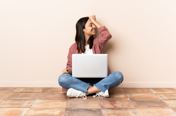 Young mixed race woman with a laptop sitting on the floor has realized something and intending the solution