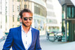 Junger Mann im Anzug mit Sonnenbrille vor Bürogebäude 