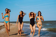 © maxbelchenko - Happy four girls having fun and running along  beach. Young women enjoying on beach holiday. Summer, relax and lifestyle concept.