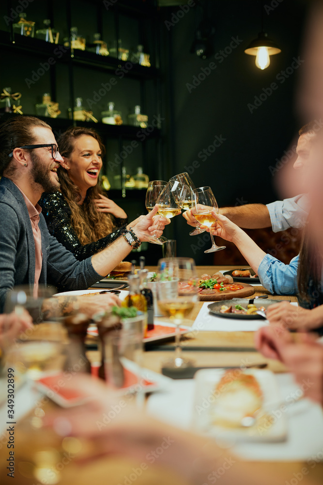 Group of best friends sitting in restaurant, making a toast and celebrating. - obrazy, fototapety, plakaty 