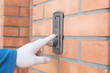 © Anna - man's hand in white protective glove press button of intercom on brick wall. protective measures from dangerous viruses. new format of communication. new rules of health safety.