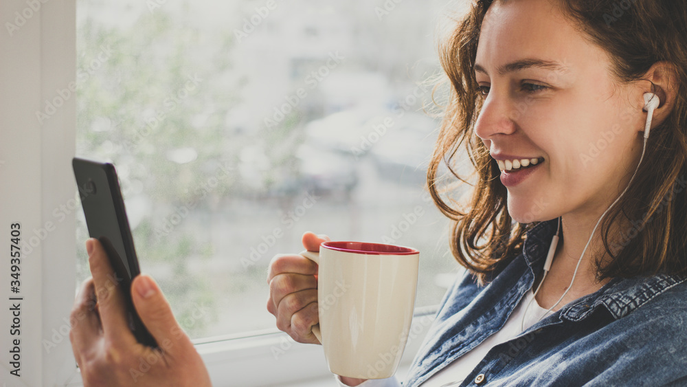 Young smiling woman in headphones using smartphone for video call ...