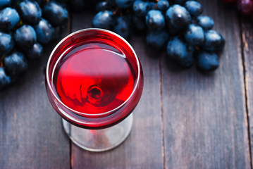 Wall Mural - glass of red wine and grapes on black wooden table background