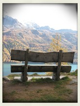 Empty Bench On Field In Front Of River And Mountain
