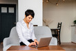 © Iryna - Woman with brown short hair using a laptop computer in the home office