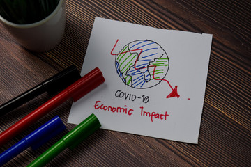 Covid 19 - Economic Impact write on sticky note isolated on wooden table.