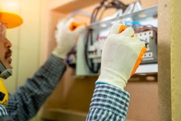 Poster - Electrician at work at House,Electrician repairing electrical box with pliers in corridor of a residential electrical system.