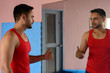 © Ranta Images - Young bearded Indian man talking to the mirror for motivation at the gym