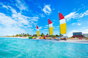 sailing multicolored catamarans is parked on the white sand on the seashore against the backdrop of 
