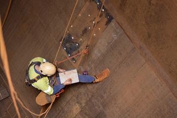 Miner rope access engineer planer  working at height abseiling into the chute,  writing, drawing defected, faulty, damage liners his planing book during shut down operation Sydney mite site, Australia