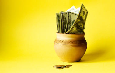 money pot on a yellow background with coins