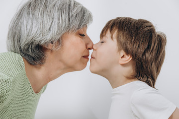 A little boy and his grandmother are having fun together against a light background