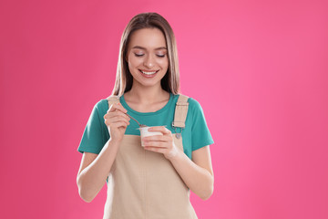 Canvas Print - Young attractive woman with tasty yogurt on pink background