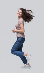 Wall Mural - 	
Laughing young woman running, having fun and enjoying life, beautiful joyful girl full length portrait. Studio shot, cut out, Isolated on grey background