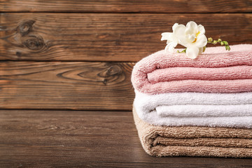 Stack of bath towels with freesia flower on wooden background