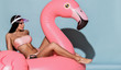 © Dmitry Lobanov - Young tanned slim woman in sexy pink beach bikini sitting relaxing on big huge pink flamingo and relaxing. Summer vibes