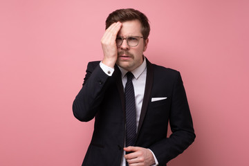 Wall Mural - Frustrated business man with a headache isolated over pink background