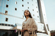 © mnelen.com - against the background of a building made of glass and concrete, a girl stands dreamily looking into the distance