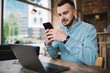 © GalakticDreamer - Freelance young man browsing smartphone while working on laptop in cafe