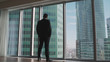 Young successful businessman standing in front of the windows, looking into the distance to the city. Successful man stands in the neoboksreb. A businessman stands in front of a window.