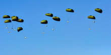 An Airdrop Of  Supplies From An Aircraft, Isolated Against The Clear Blue Sky.
