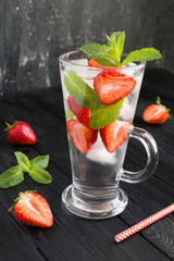 Wall Mural - Infused or detox water with strawberry  and  mint  in the glass on the dark  background. Closeup. Location vertical.