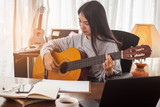 Fototapeta  - Young Asian woman playing guitar at home for relax.