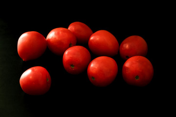 Red ripe tomatoes on black background. Top view with copy space