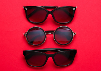 Wall Mural - Stylish fashionable sunglasses on red paper background. Top view. Minimalism