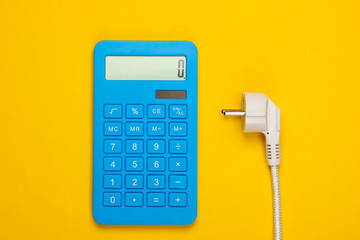 Calculator with a power plug on a yellow background. Calculation of energy consumption costs. Top view