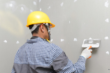 interior decoration construction furniture builtin.Plasterer in working uniform plastering the wall indoors.