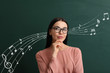 Thoughtful female music teacher near blackboard in classroom