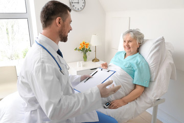 Poster - Male doctor working with elderly patient in hospital room