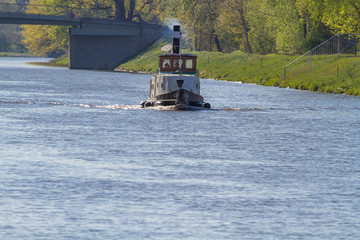 
The boat sails on the Vltava river near the bridge in the vicinity is a green landscape and Prague architecture in the spring