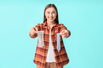 Sticker - Young woman with male and female condoms on color background