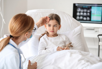 Female doctor working with little girl in hospital room