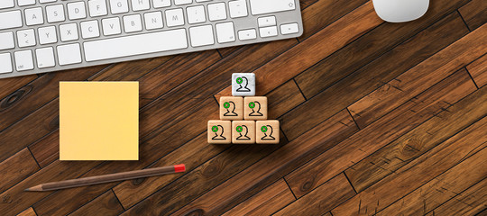 stacked cubes with many people symbols with office items on wooden background 