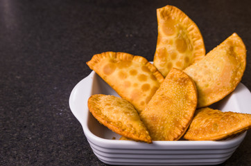 Great photo of Brazilian pastry (pastel), traditional dish of Brazilian cuisine in a dish on a black granite background.