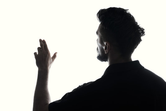 Fototapete - Silhouette of male person touches empty space with hand , back view back lit over white