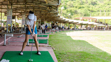 Healthy Sport.  Asian Sporty Woman Swing Golf Ball Practice At Golf Driving Range On Evening On Time For Healthy Sport. Lifestyle And Sport Concept