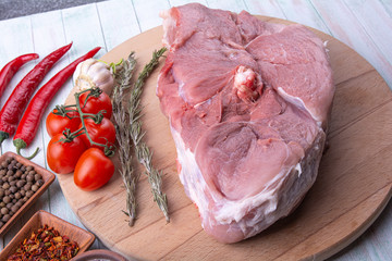 Wall Mural - raw piece of pork meat, cherry tomatoes, chili peppers on a round wooden cutting Board